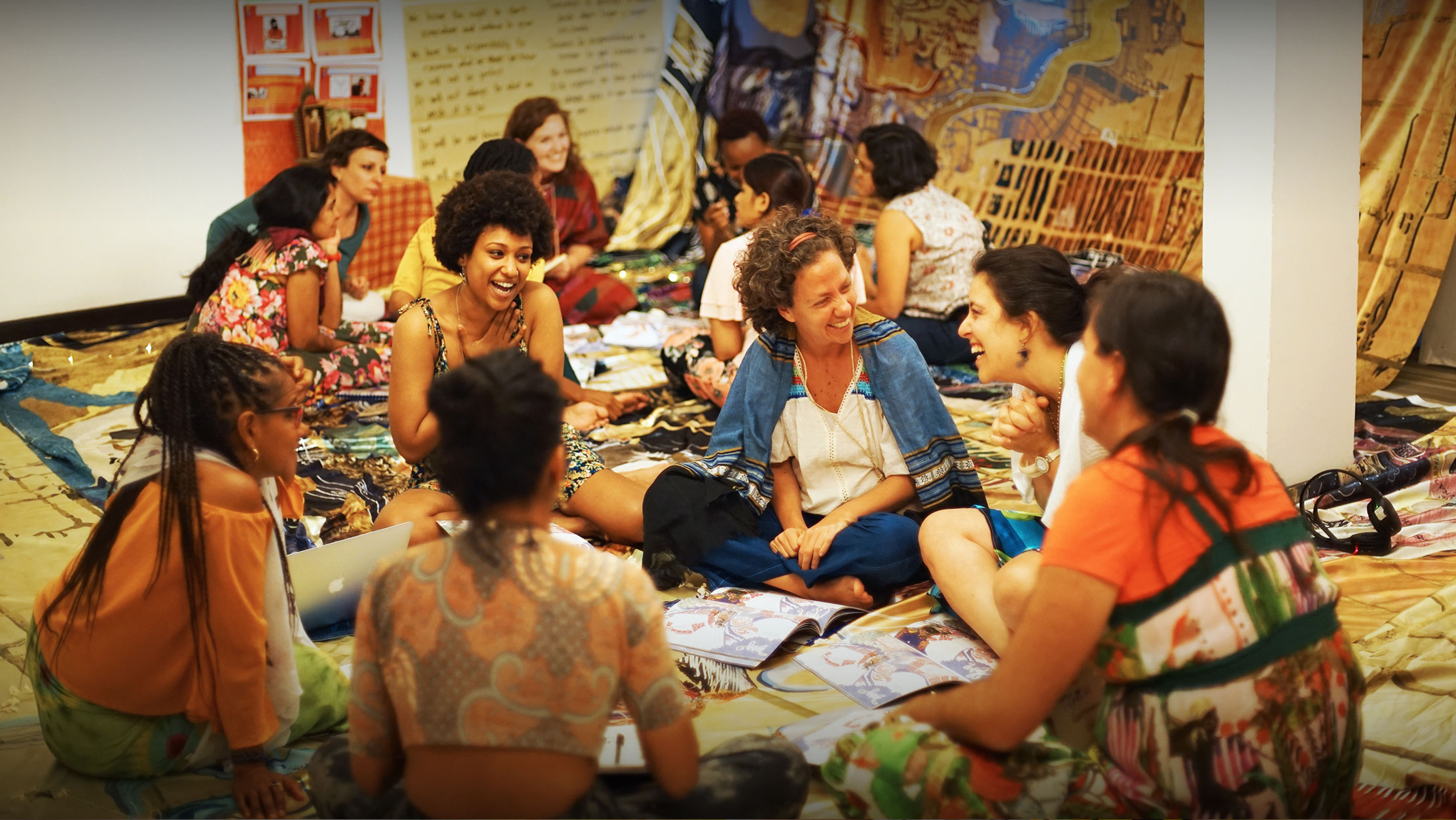 Women happily discussing sat cross legged on the floor