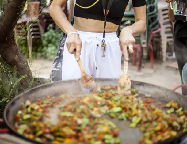 A person mixing ingredients in large paella pan
