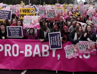 People at a raleigh with boards, stood behind a pro-baby banner