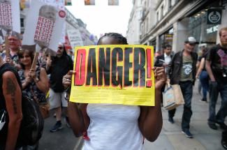 Protester holding a flyer that reads "Danger - Trump and the Far Right."