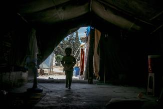 Unrecognizable child walking in tent. Photo by Ahmed akacha. 