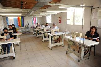 Photo of five trans and travesti people behind sewing machines in the workshop of the Nadia Echazú cooperative