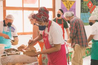 Photo of people in facemasks and aprons cooking together