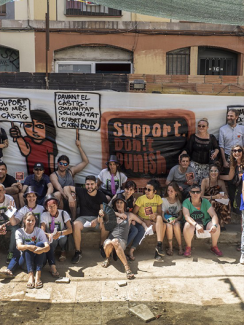 A crowd of people sitting in front of a banner which says ‘support, don't punish”;