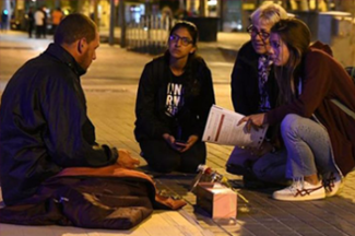 Photo of four people sitting on the ground and talking