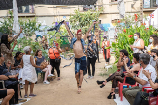 Photo people with plants around them, most of them sitting and clapping to a person who is walking in the middle