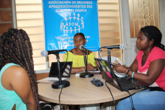 Photo of three women sitting around the table and talking in mics.