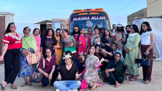 A group of people posing for a photo in front of a colorful bus. 